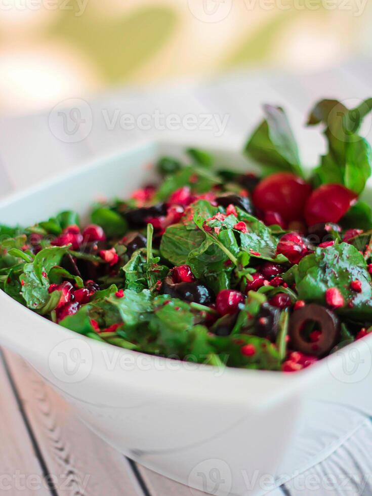 Rocca salada azedo com romã sementes, azeitonas e ervas folhas servido dentro prato isolado em mesa fechar-se topo Visão do saudável orgânico Comida foto