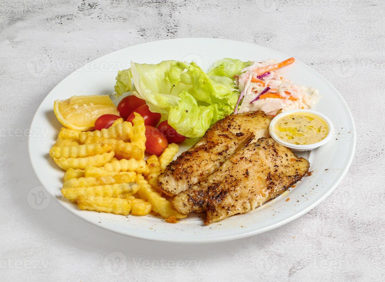 grelhado dory peixe com limão, salada, tomate e mergulho servido dentro prato isolado em banana folha topo Visão do Cingapura Comida foto