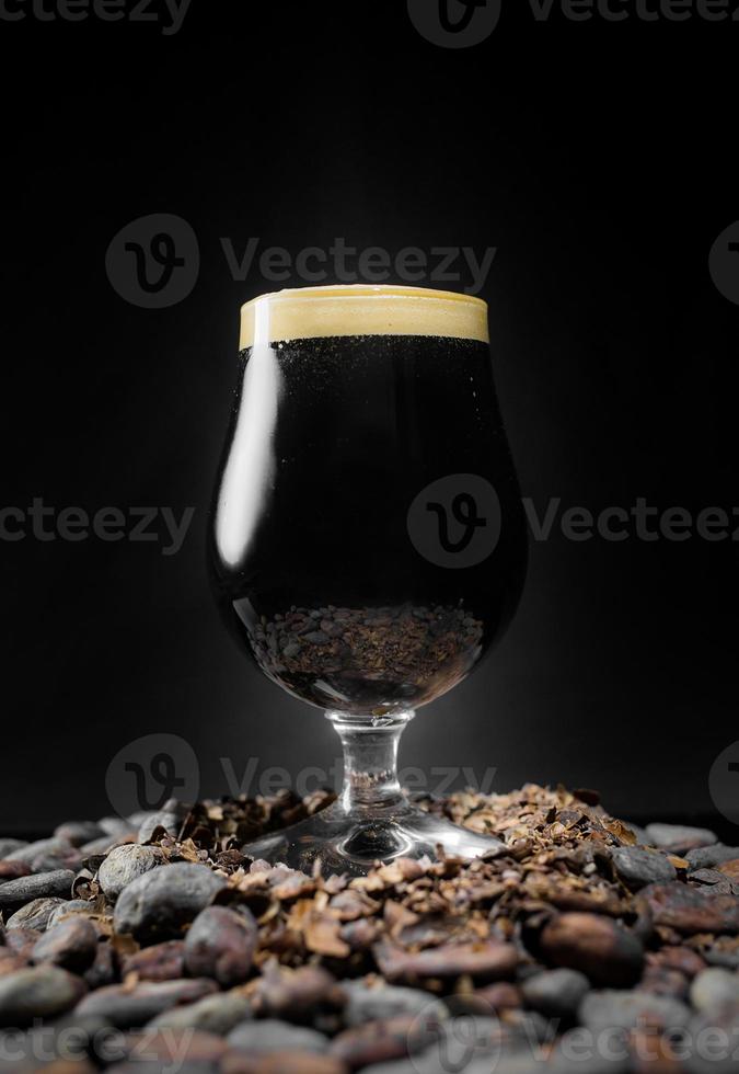 cerveja preta escura e forte sobre uma pilha de grãos de cacau foto