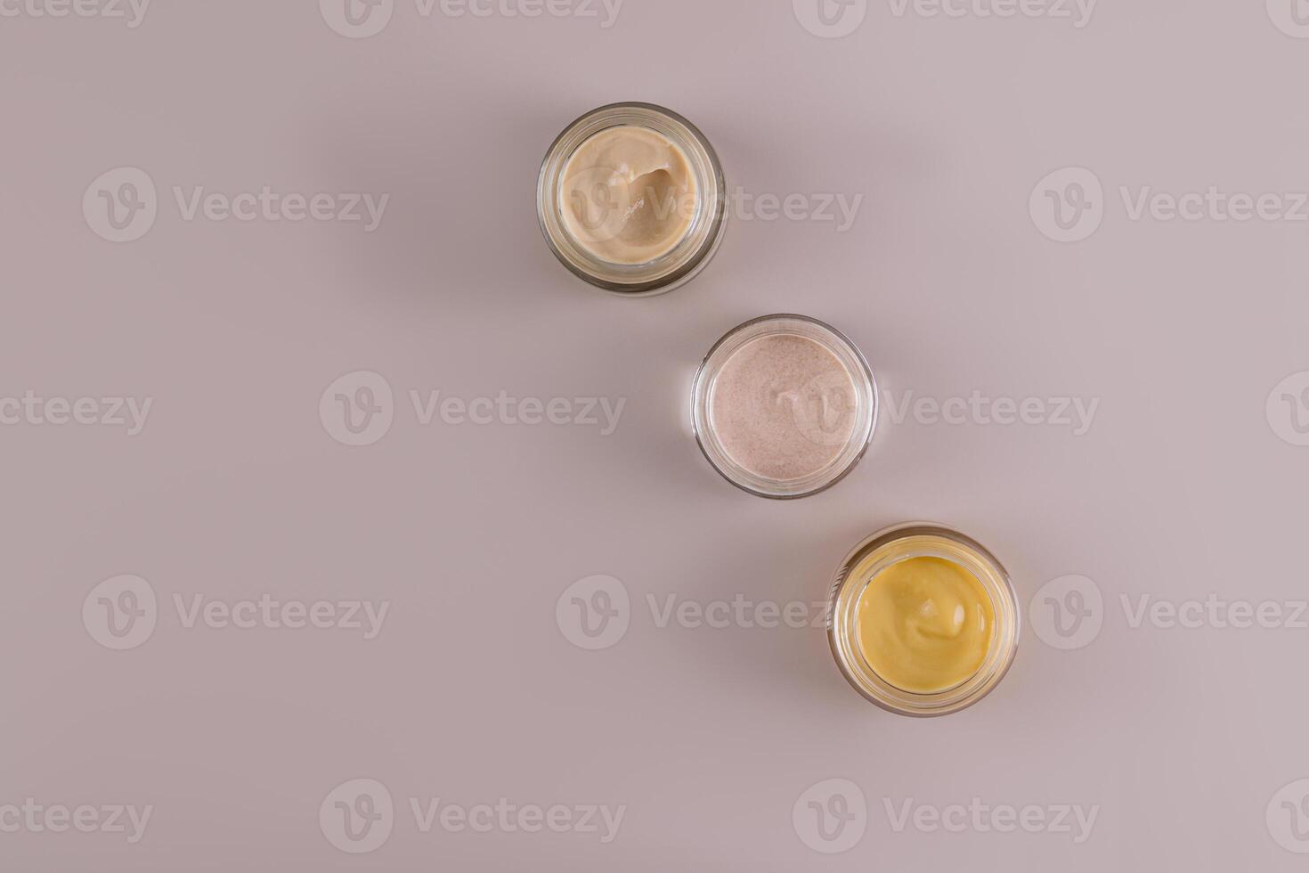 uma conjunto do vidro frascos com Cosmético creme do diferente cores para face e corpo pele Cuidado. Projeto. embalagem. produtos apresentação. topo visualizar. brincar foto