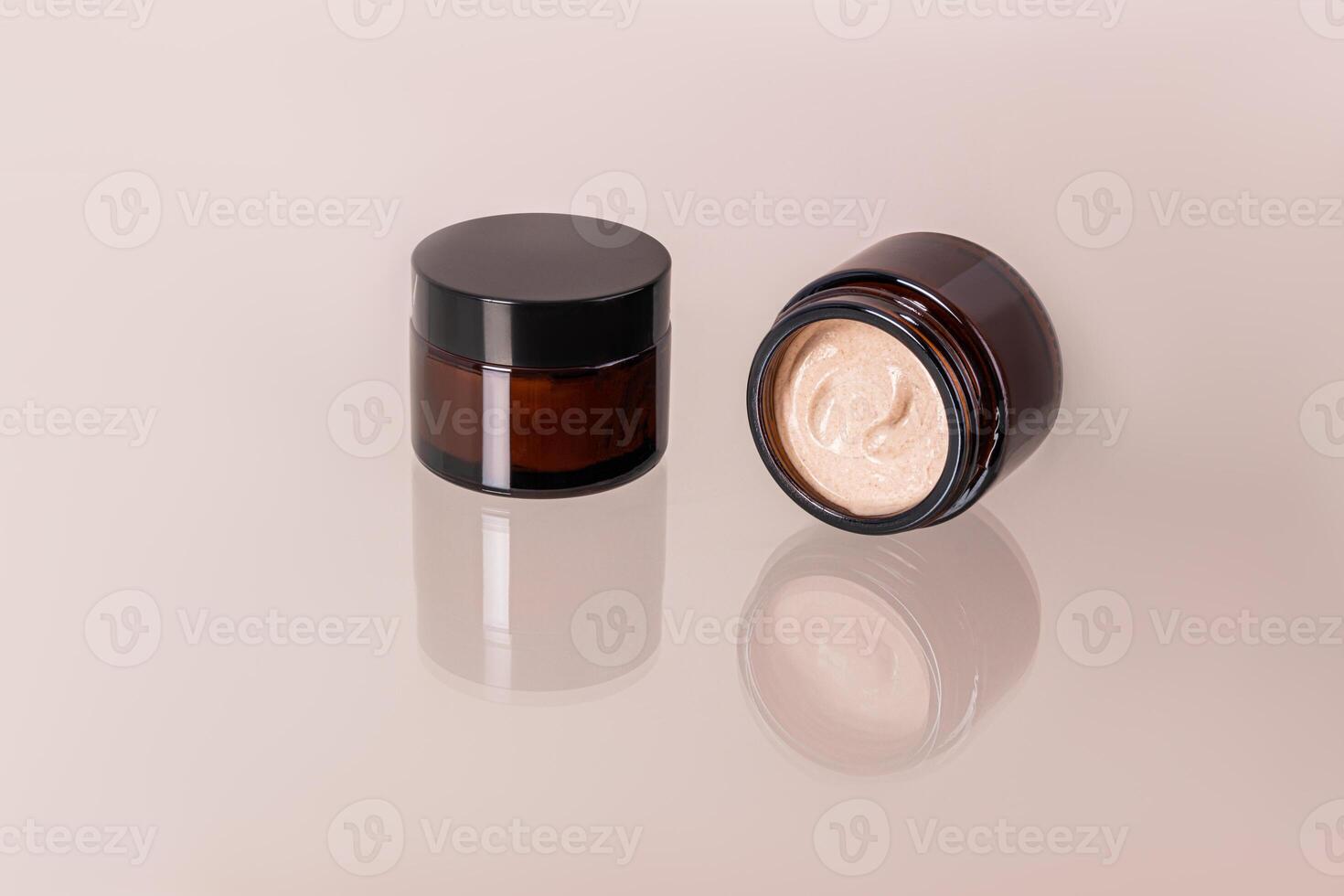 fechadas e aberto frascos com Cosmético creme para face e corpo pele Cuidado em vidro superfície com reflexão do frascos. delicado textura do bege creme. foto