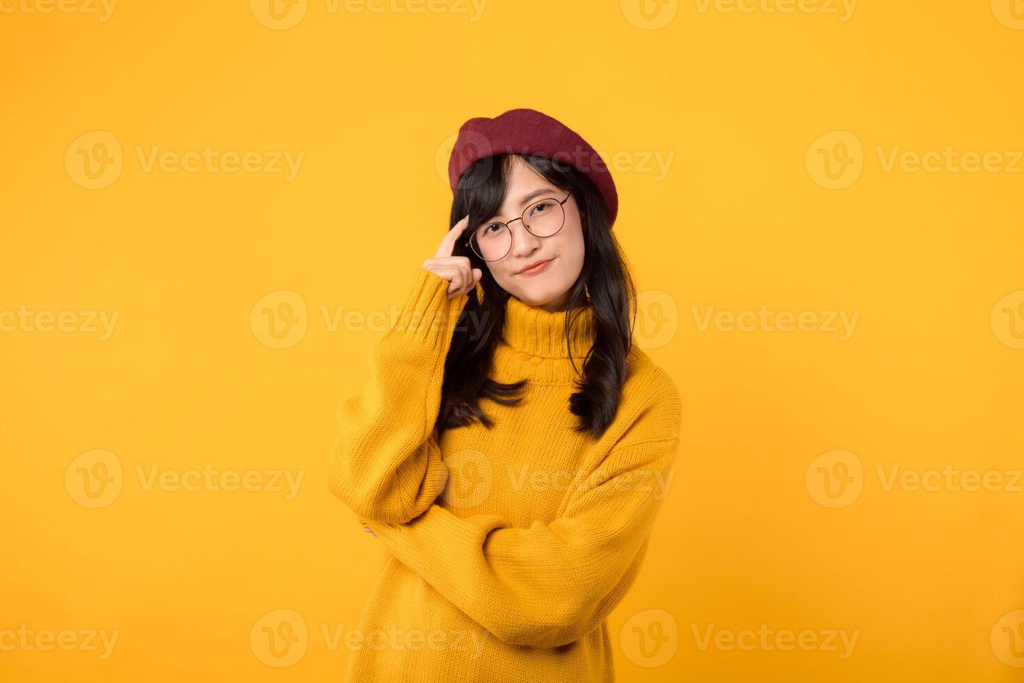 retrato jovem ásia mulher 30s feliz sorrir vestindo amarelo suéter e vermelho boina mostrando pensando corpo língua isolado em amarelo fundo. foto