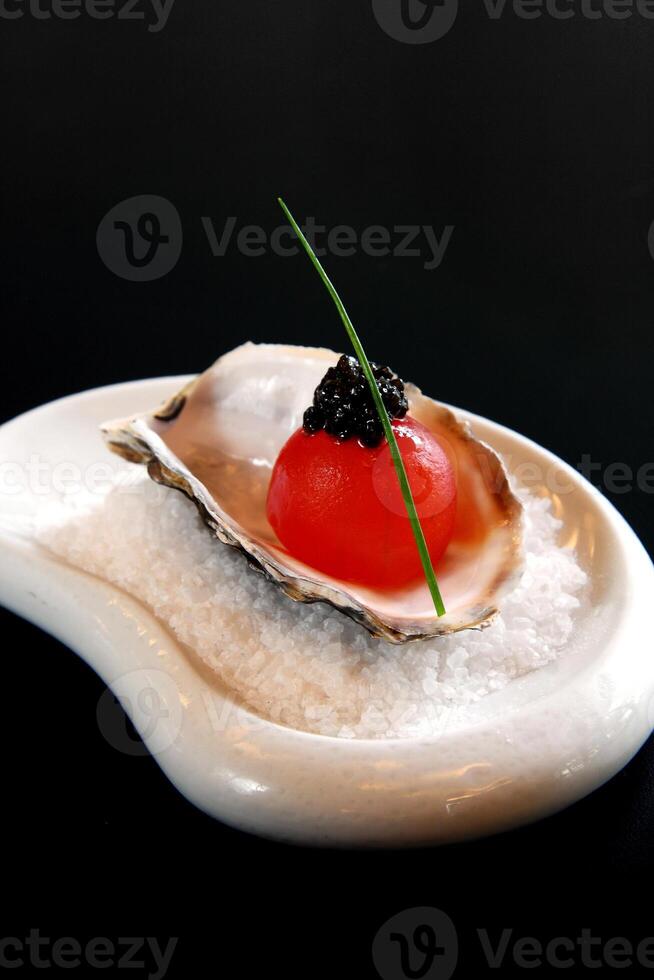 Melancia bola com caviar dentro ostra com sal foto