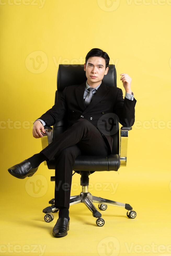 retrato do ásia masculino homem de negocios. vestindo uma terno e posando em uma amarelo fundo foto