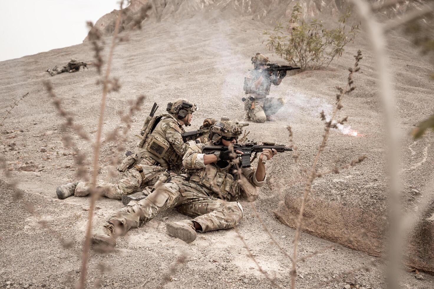 soldados dentro camuflar uniformes visando com seus rifles prontos para fogo durante militares Operação dentro a deserto soldados Treinamento dentro uma militares Operação foto