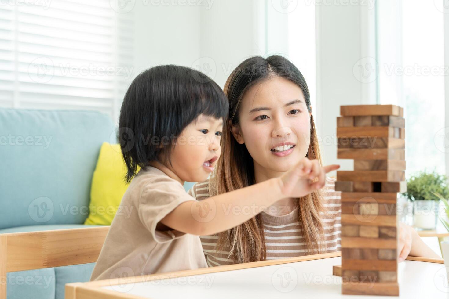 Ásia feliz solteiro mãe jogando Aprendendo jogos janga com a pequeno garoto. engraçado família é feliz e animado dentro a casa. pai e filho tendo Diversão gastos Tempo junto. feriado, fim de semana, vago. foto