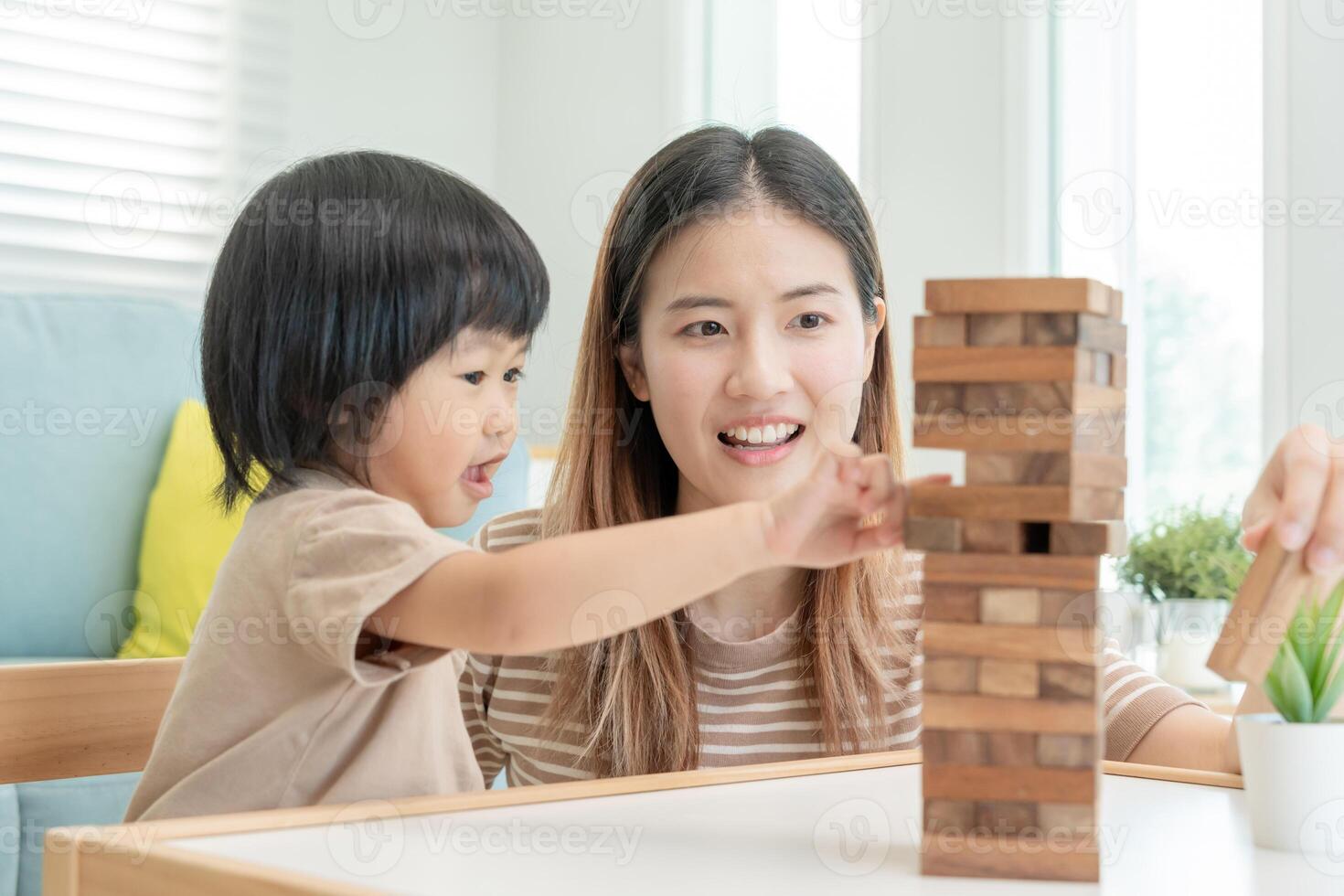 Ásia feliz solteiro mãe jogando Aprendendo jogos janga com a pequeno garoto. engraçado família é feliz e animado dentro a casa. pai e filho tendo Diversão gastos Tempo junto. feriado, fim de semana, vago. foto