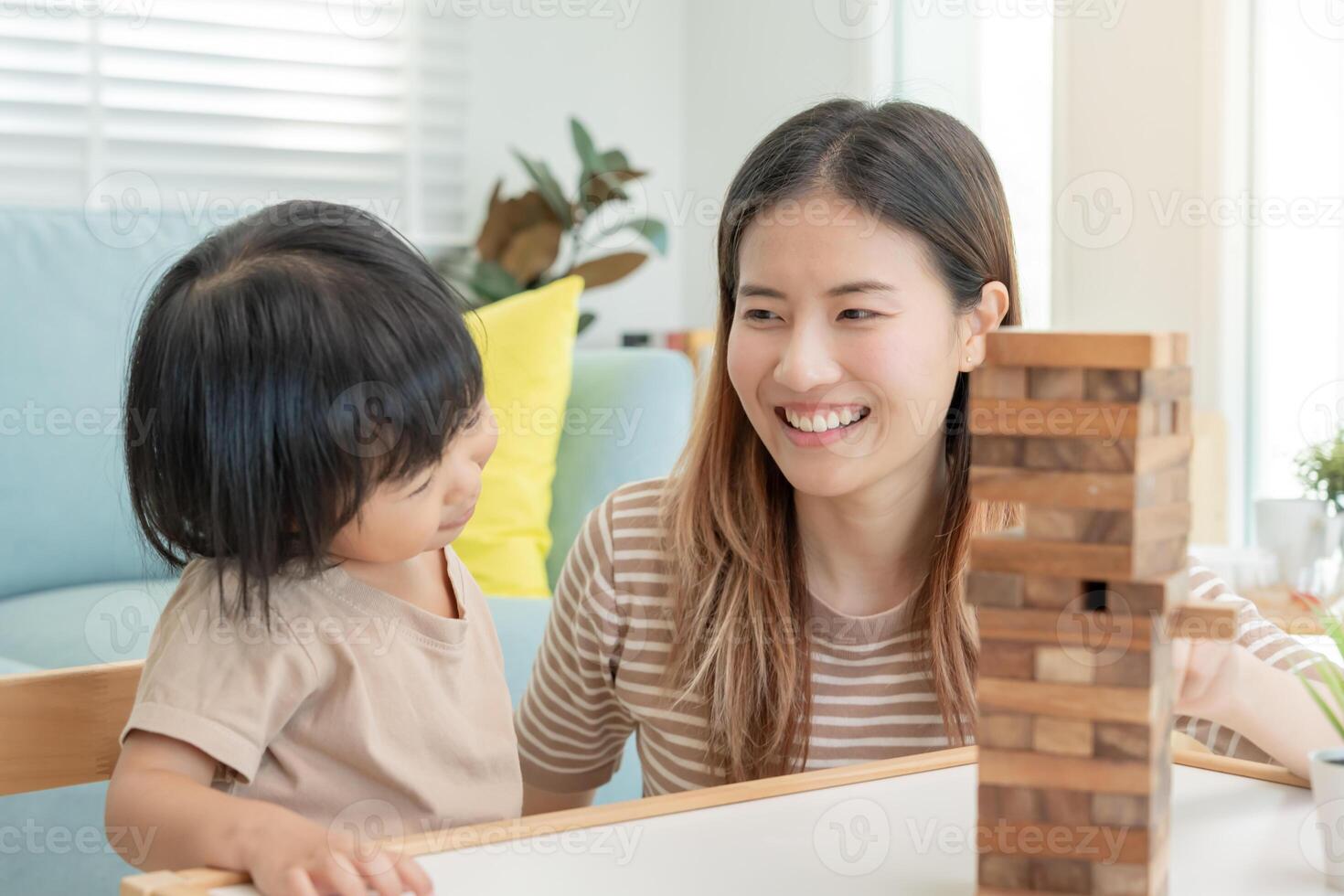 Ásia feliz solteiro mãe jogando Aprendendo jogos janga com a pequeno garoto. engraçado família é feliz e animado dentro a casa. pai e filho tendo Diversão gastos Tempo junto. feriado, fim de semana, vago. foto