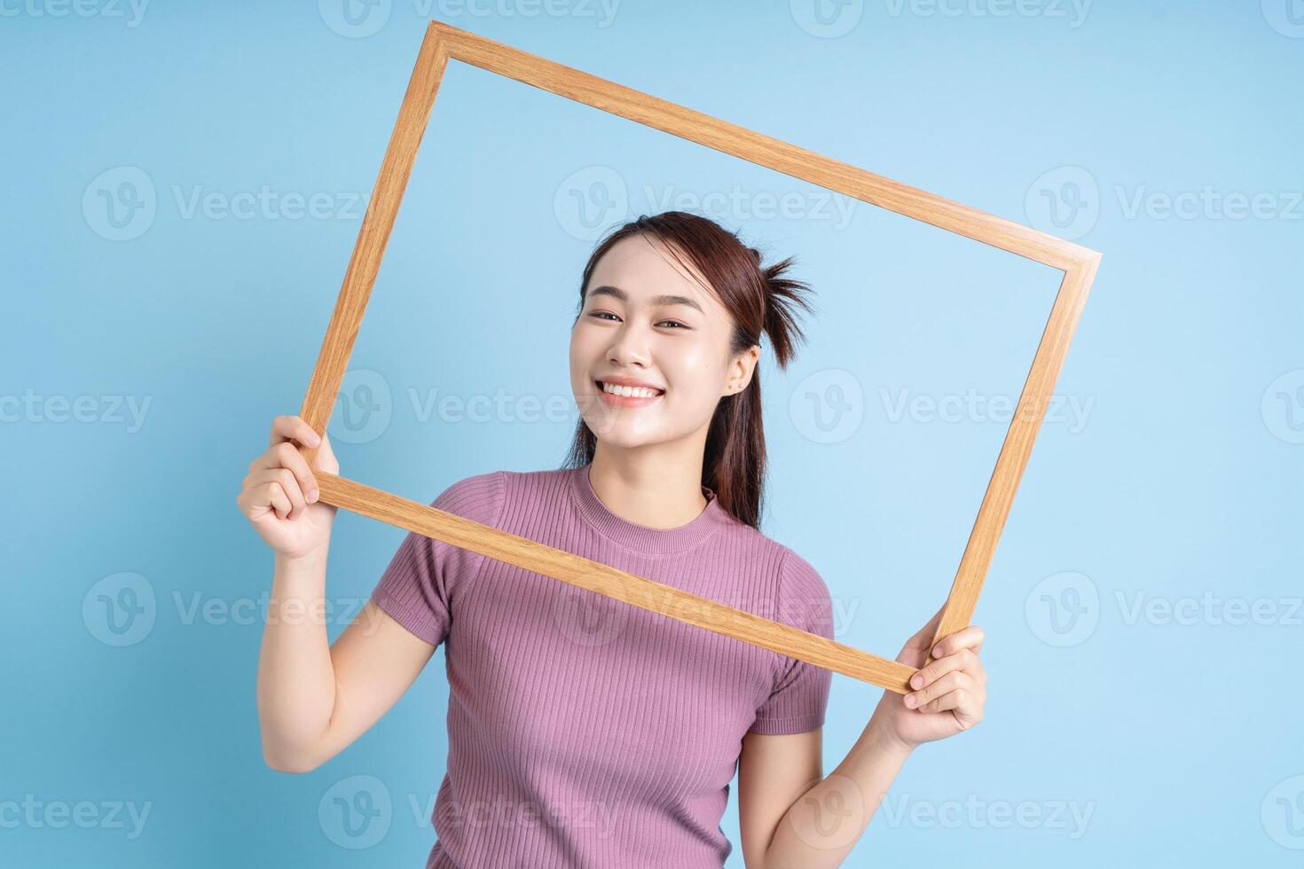 jovem ásia mulher segurando foto quadro, Armação em azul fundo