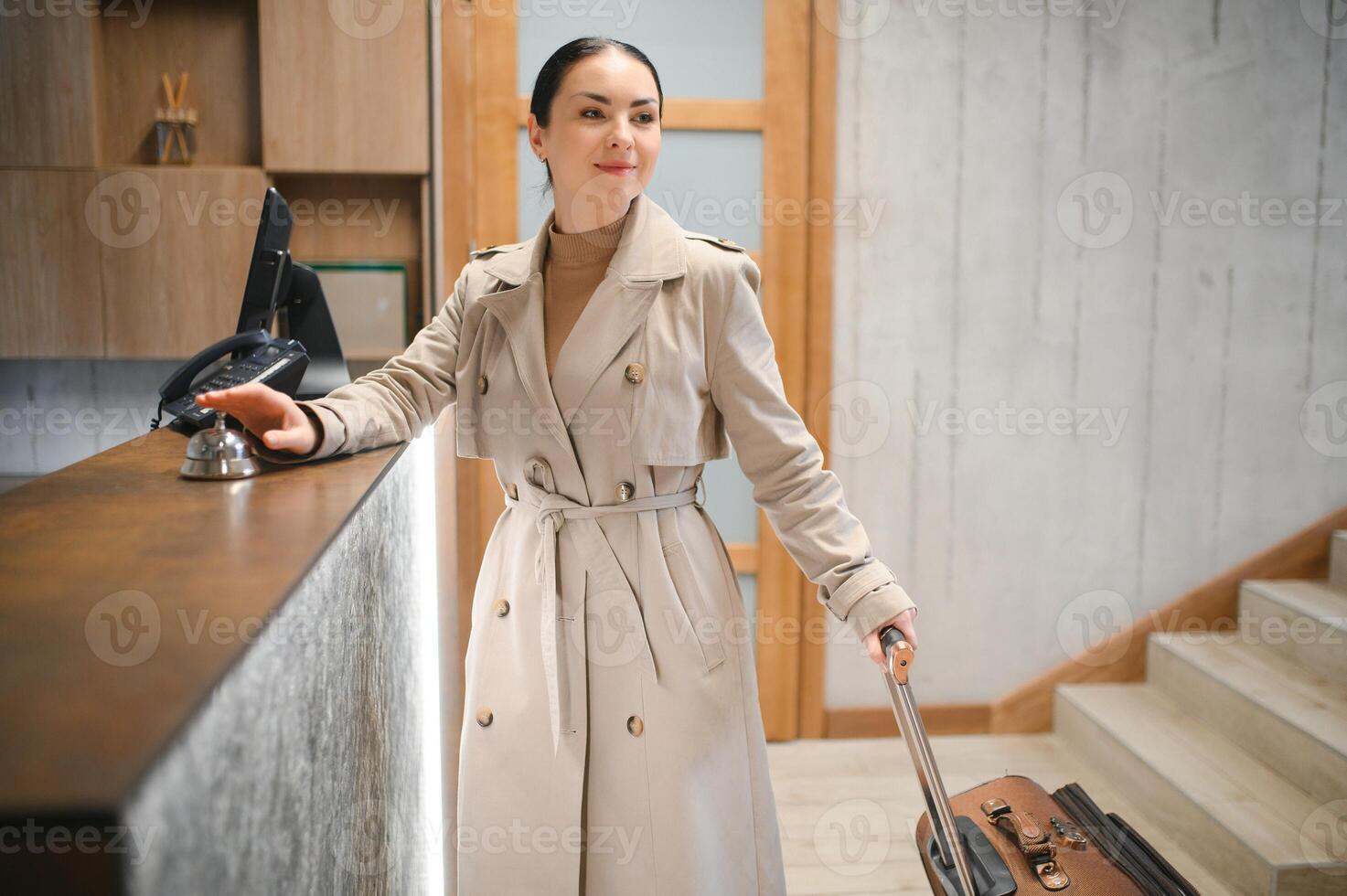 elegante o negócio mulher com viagem carrinho bagagem dentro hotel lobby foto