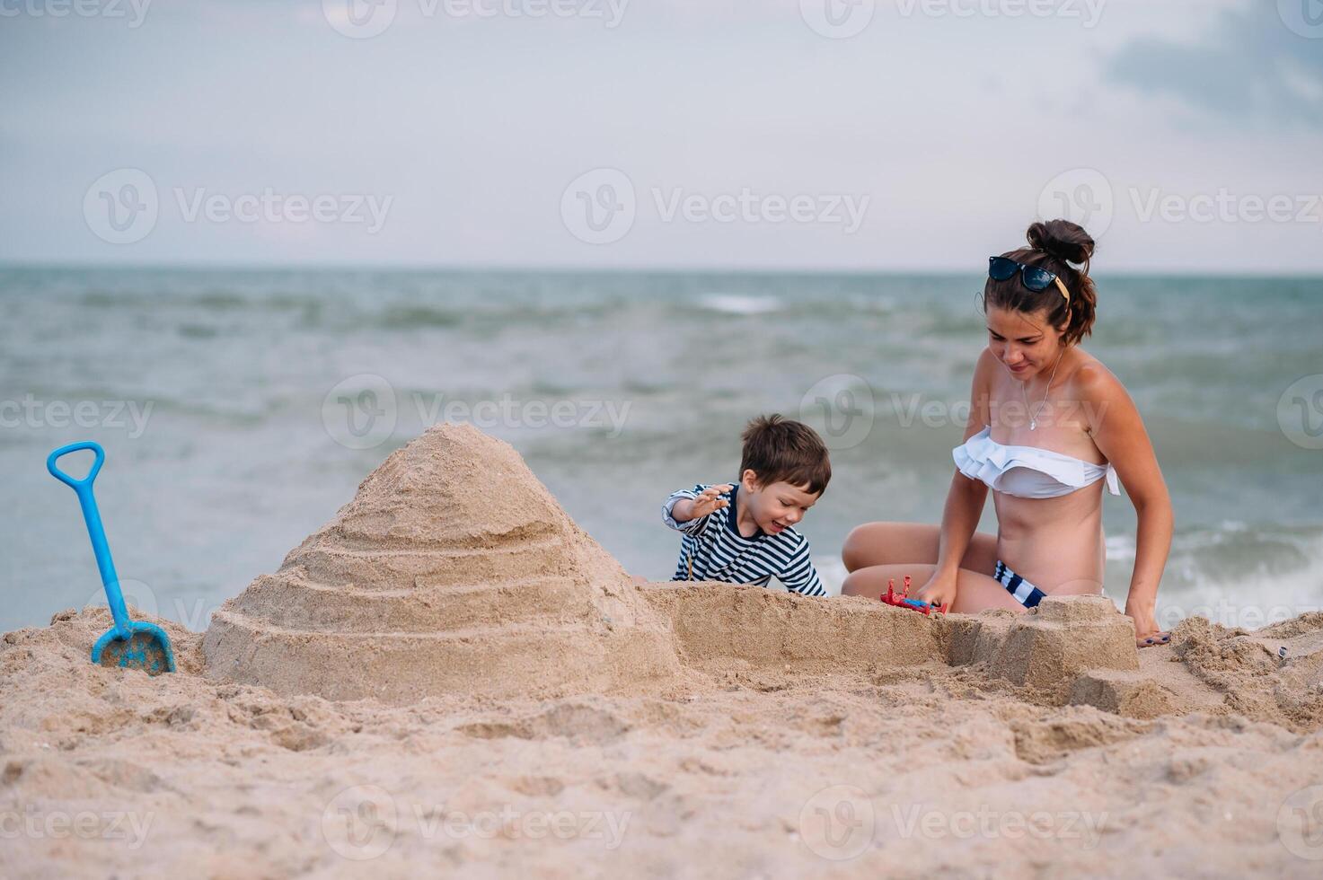 mãe e filho jogando em a de praia às a pôr do sol tempo. conceito do amigáveis família foto