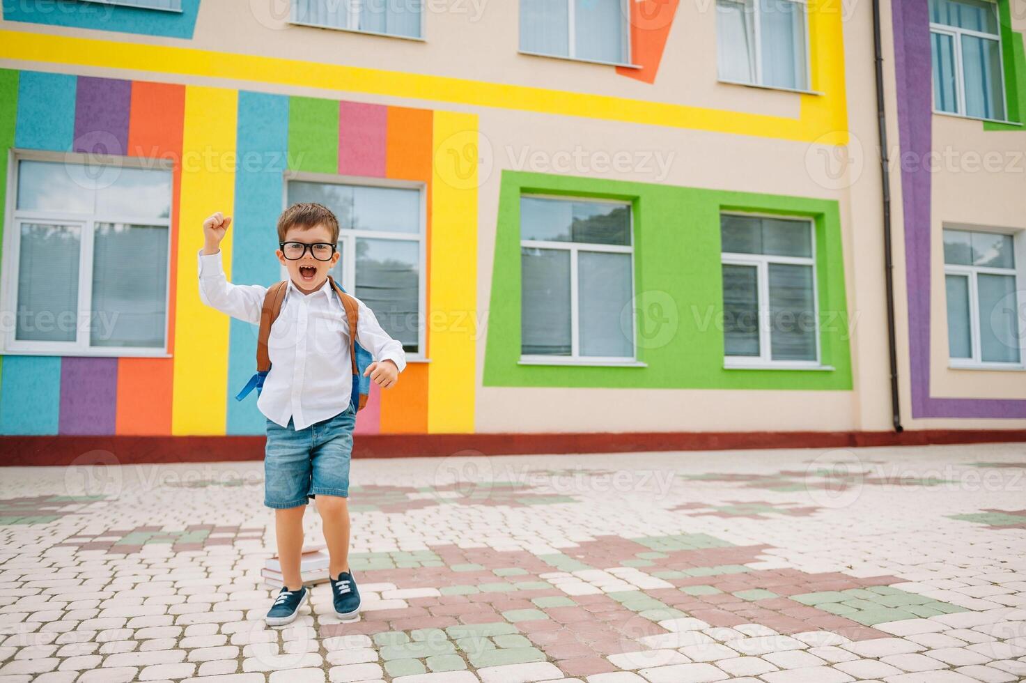 costas para escola. feliz sorridente Garoto dentro óculos é indo para escola para a primeiro tempo. criança com mochila e livro ao ar livre. começando do aulas. primeiro dia do outono foto