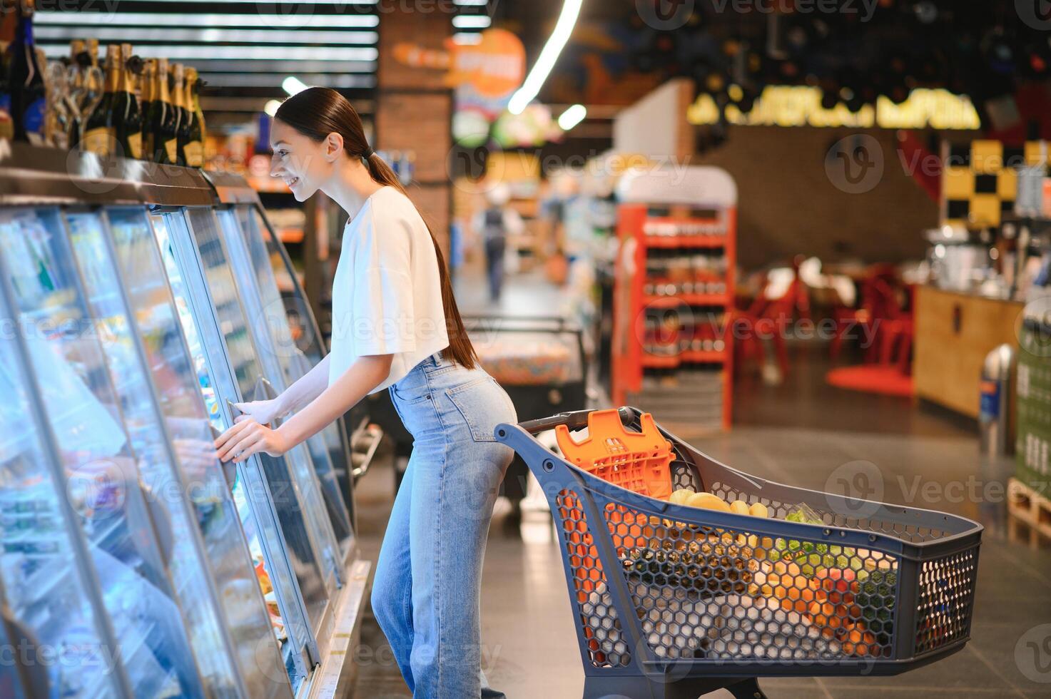 jovem mulher com uma compras saco Como uma cliente comprando peixe às a refrigerado estante dentro a supermercado foto