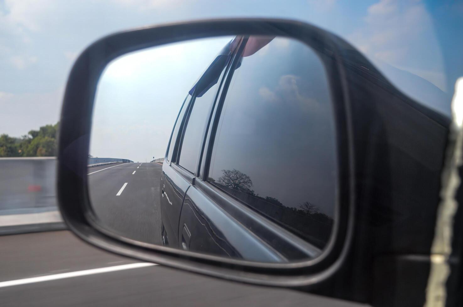 visão traseira espelho Visão do uma carro viajando às Alto Rapidez em uma Pedágio estrada foto