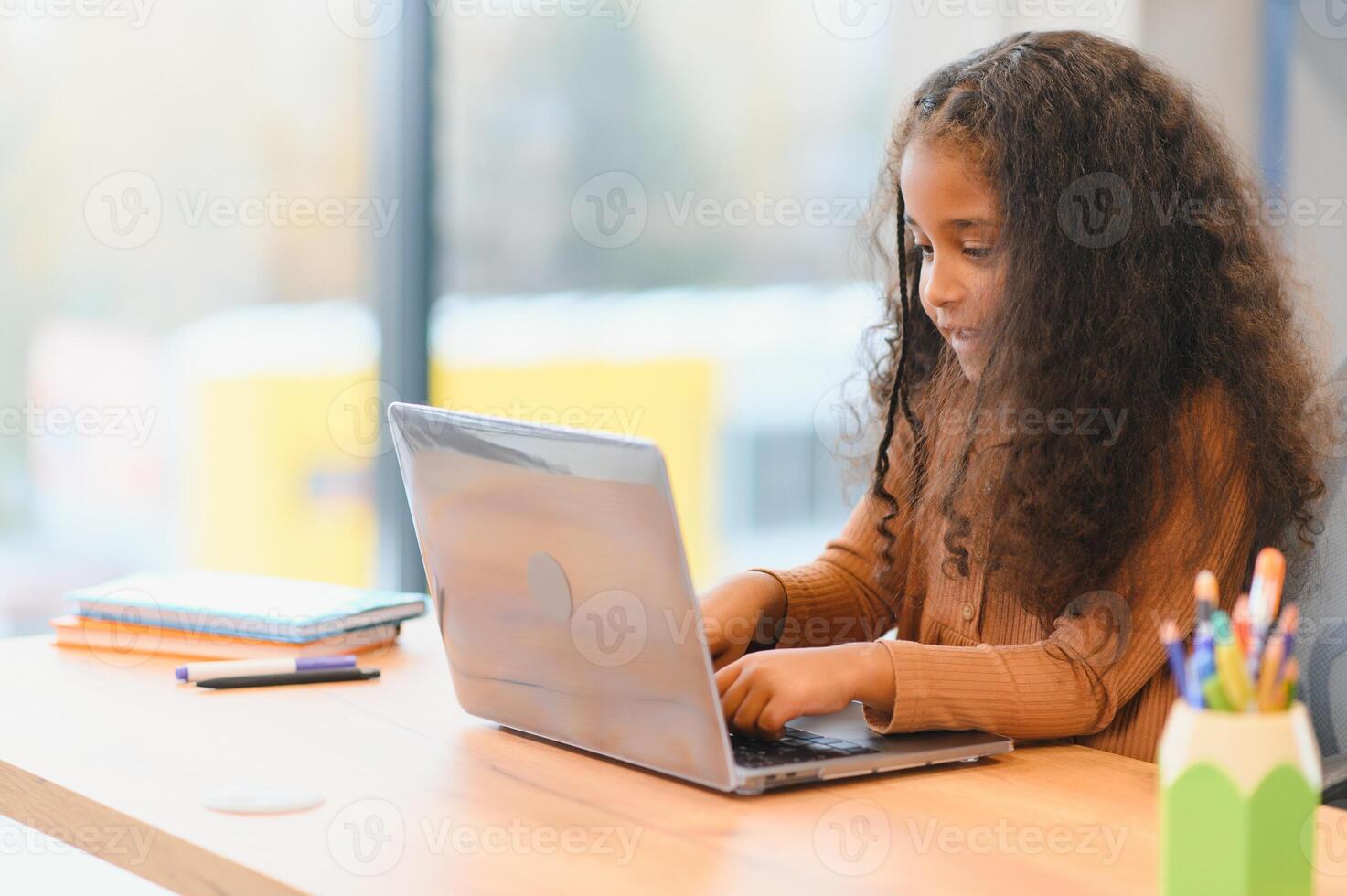 africano americano menina sentado às mesa, usando computador portátil para conectados lição foto