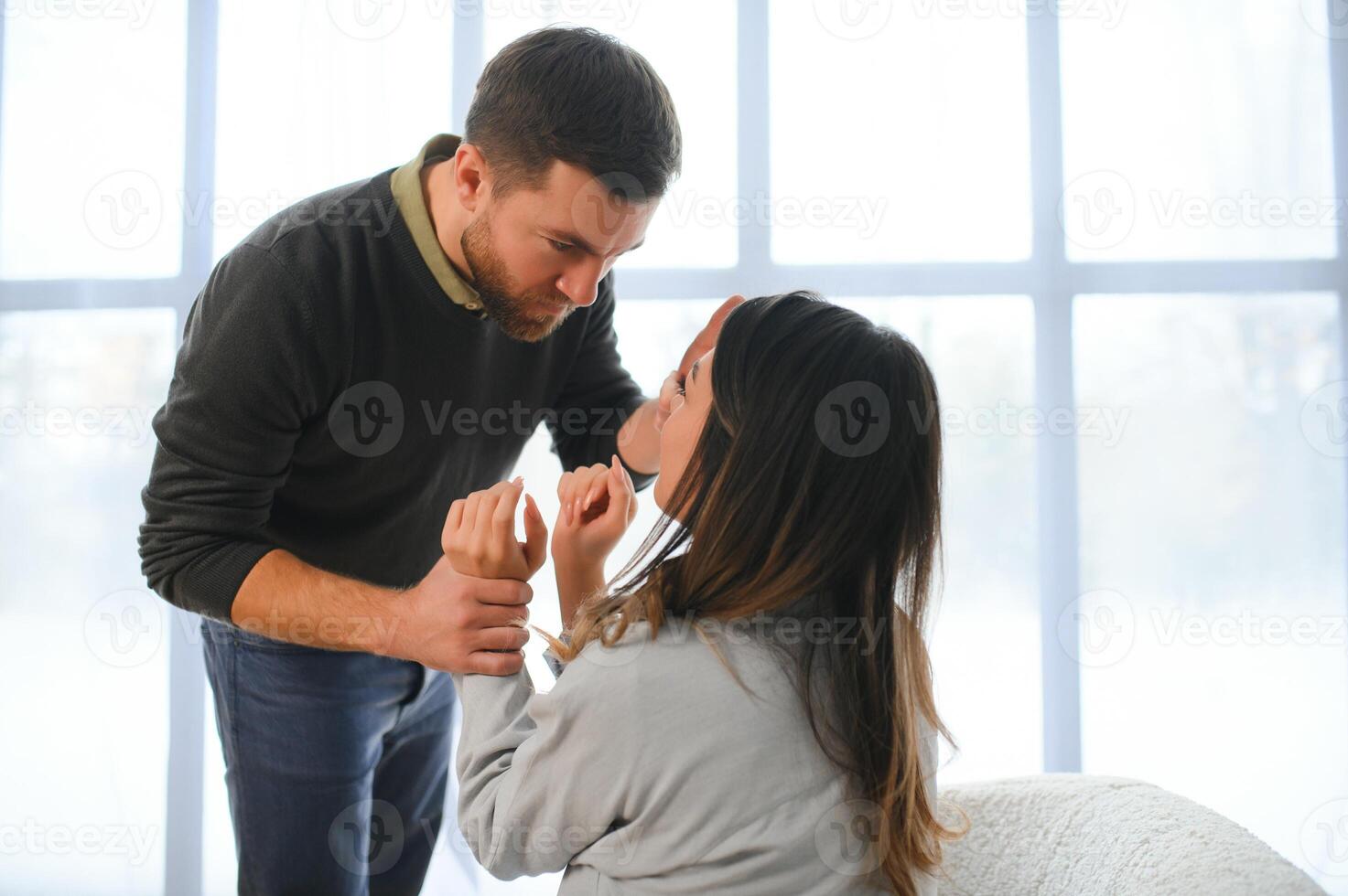 briga, violência e marido batidas esposa às lar. Bravo homem levanta dele punho às assustado mulher. foto