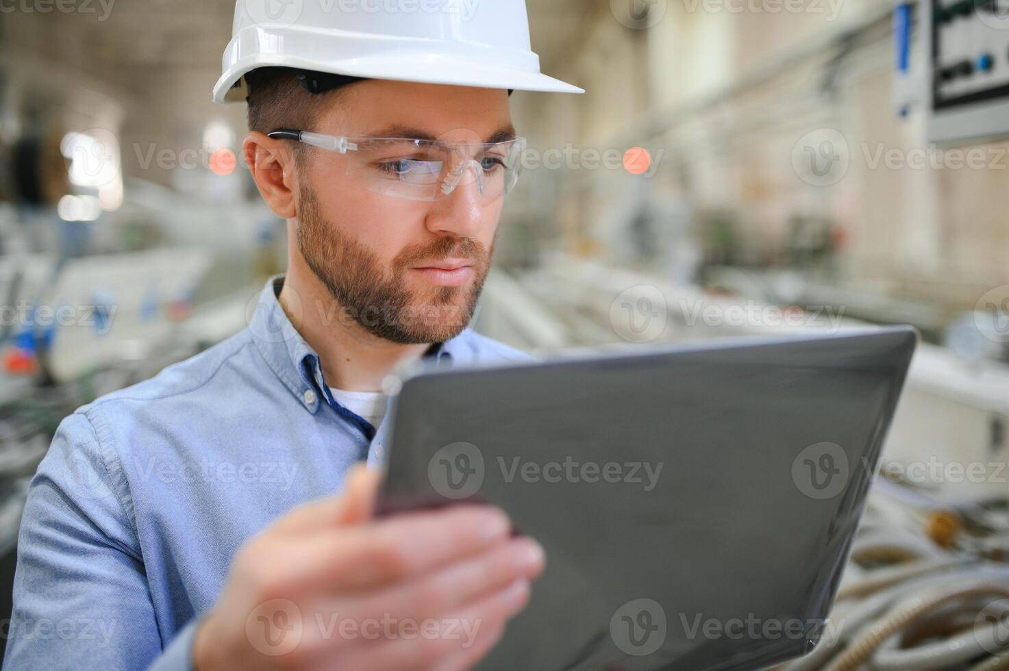 engenheiro dentro capacete de segurança é usando uma computador portátil dentro uma pesado indústria fábrica foto