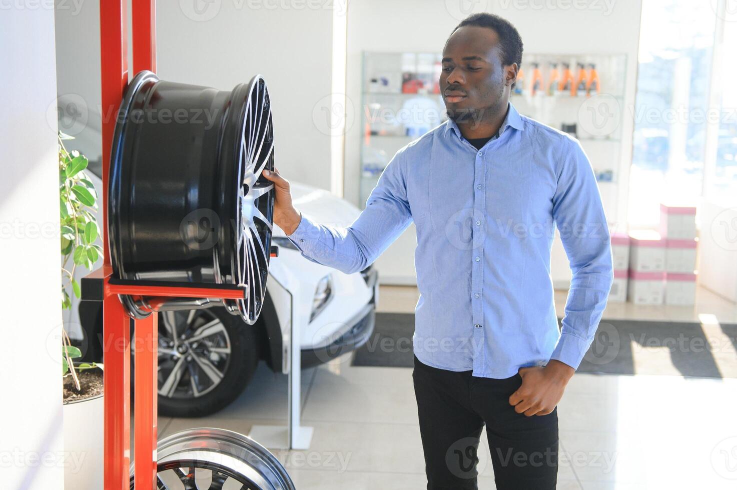 a africano homem compra carro aros dentro a auto partes loja foto
