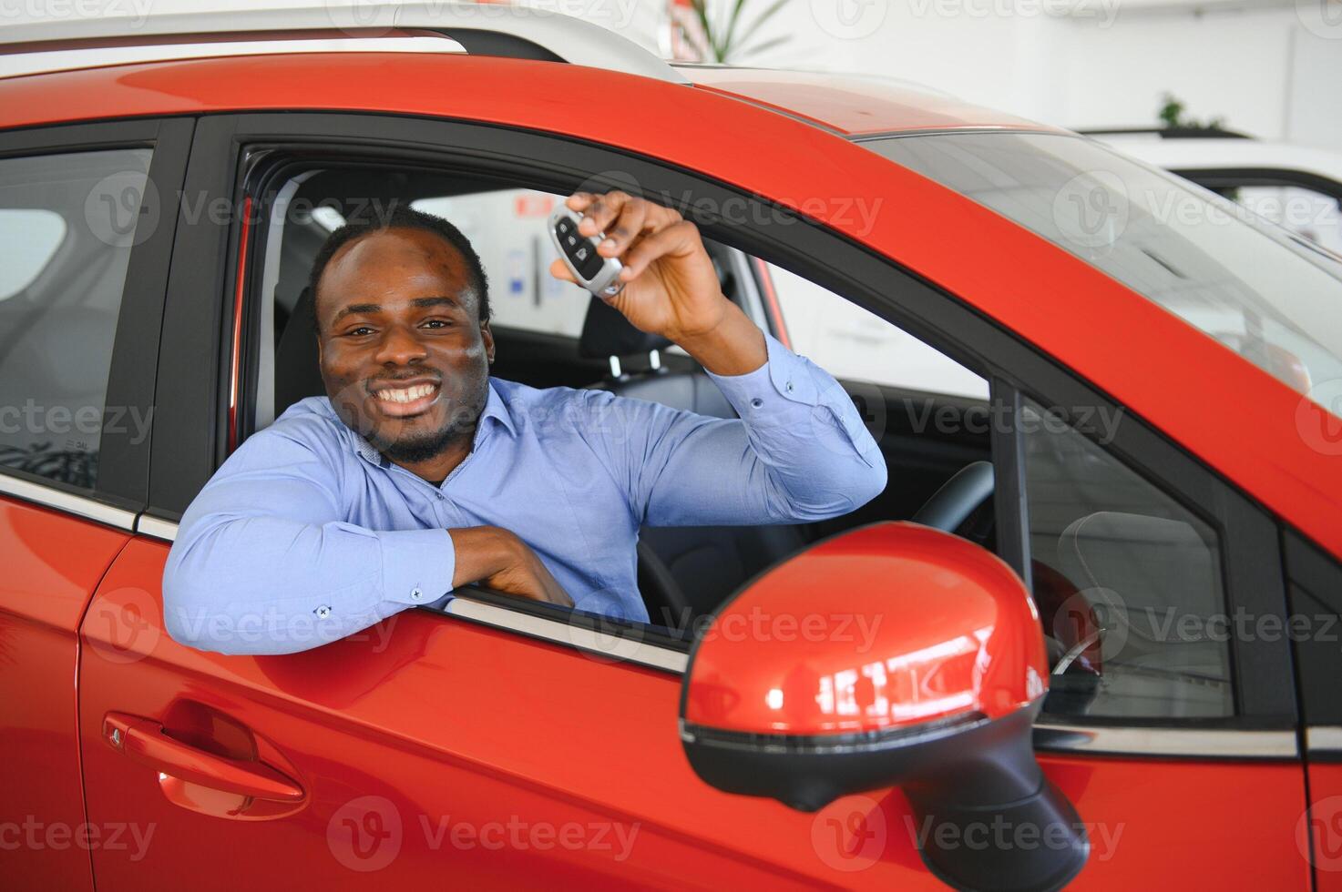 comprador de veículo africano feliz dentro de seu carro novo com chave do carro foto