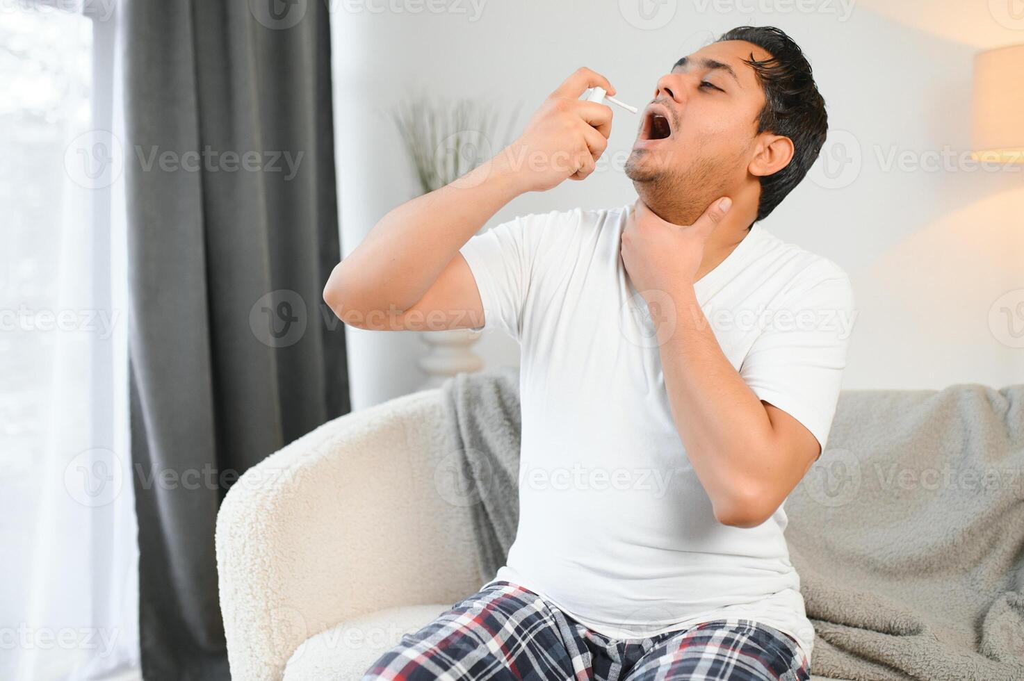indiano homem doente às lar, frio, gripe. uma homem usa uma garganta spray foto