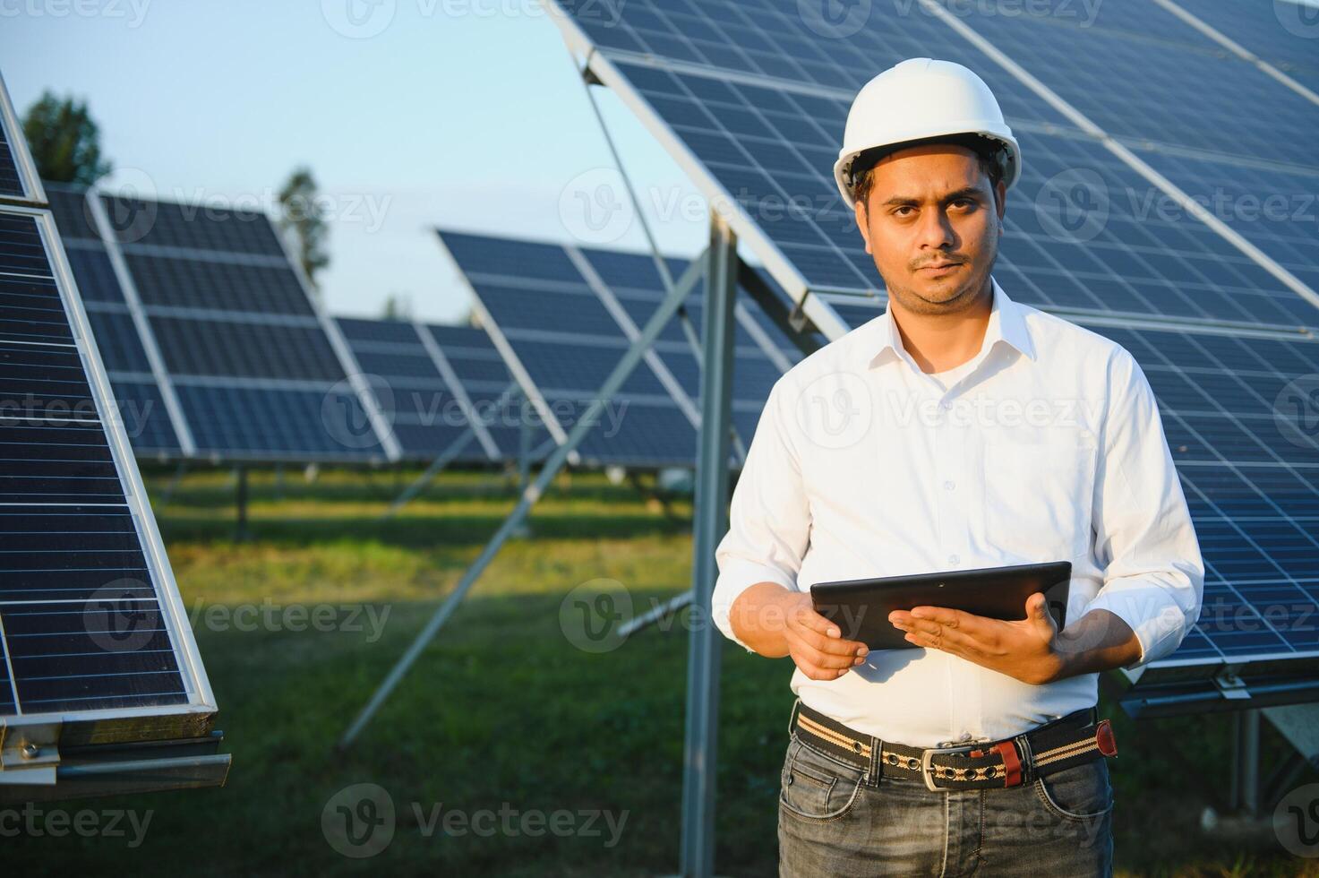 a indiano masculino engenheiro trabalhando em uma campo do solar painéis. a conceito do renovável energia foto