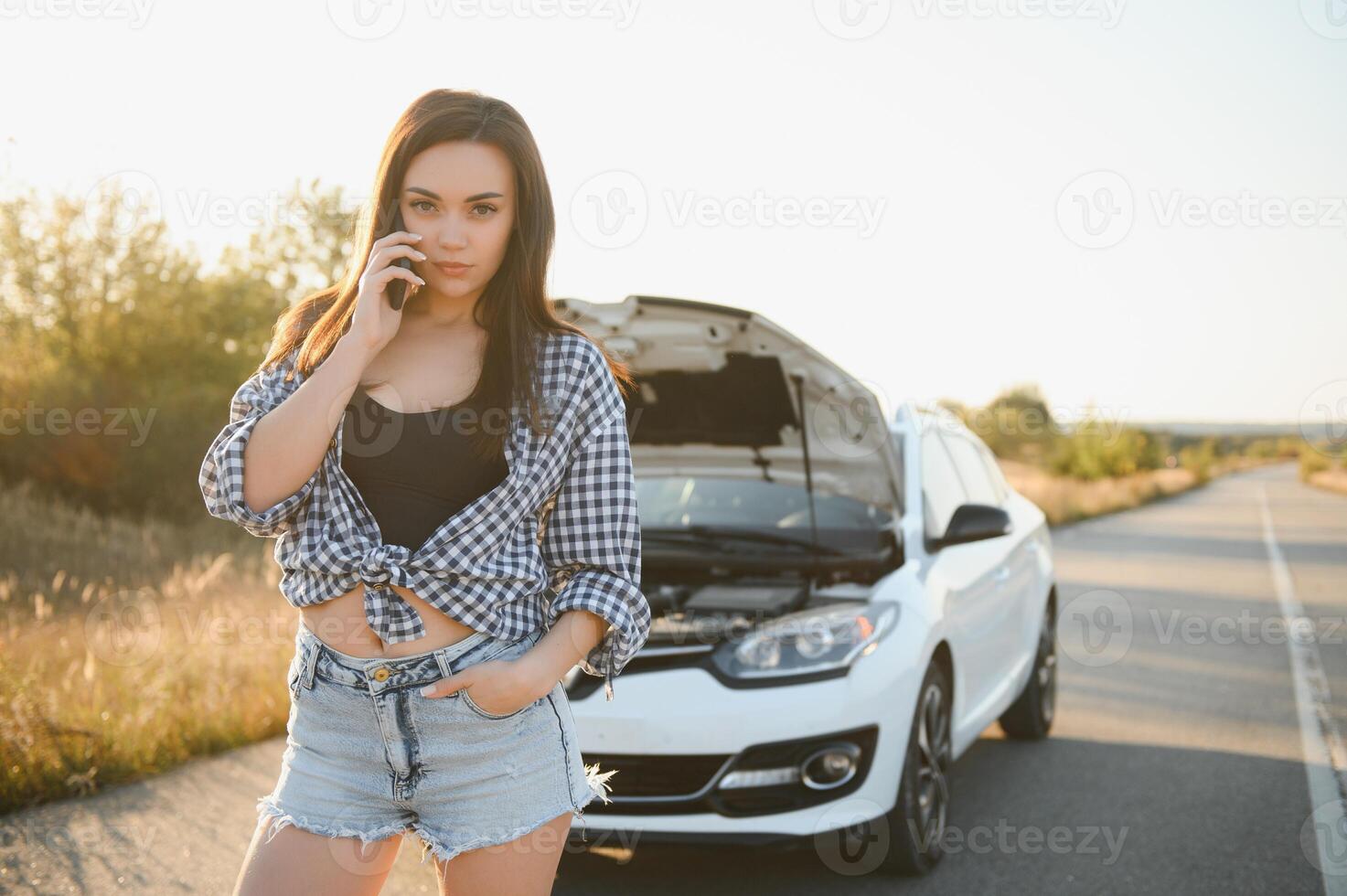 a jovem menina quebrou a carro e ela aberto a de capuz e tentou para reparar a carro em a estrada. uma mulher chamadas em uma Smartphone com uma carro evacuação serviço foto