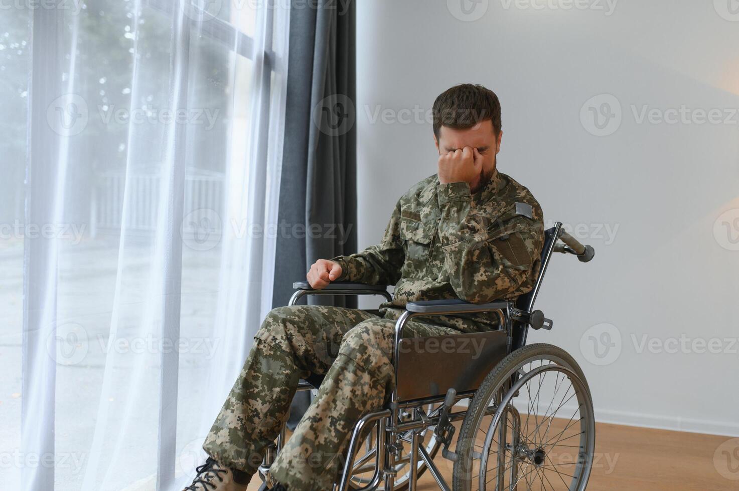 bonito soldado sentado dentro uma cadeira de rodas em cinzento fundo foto