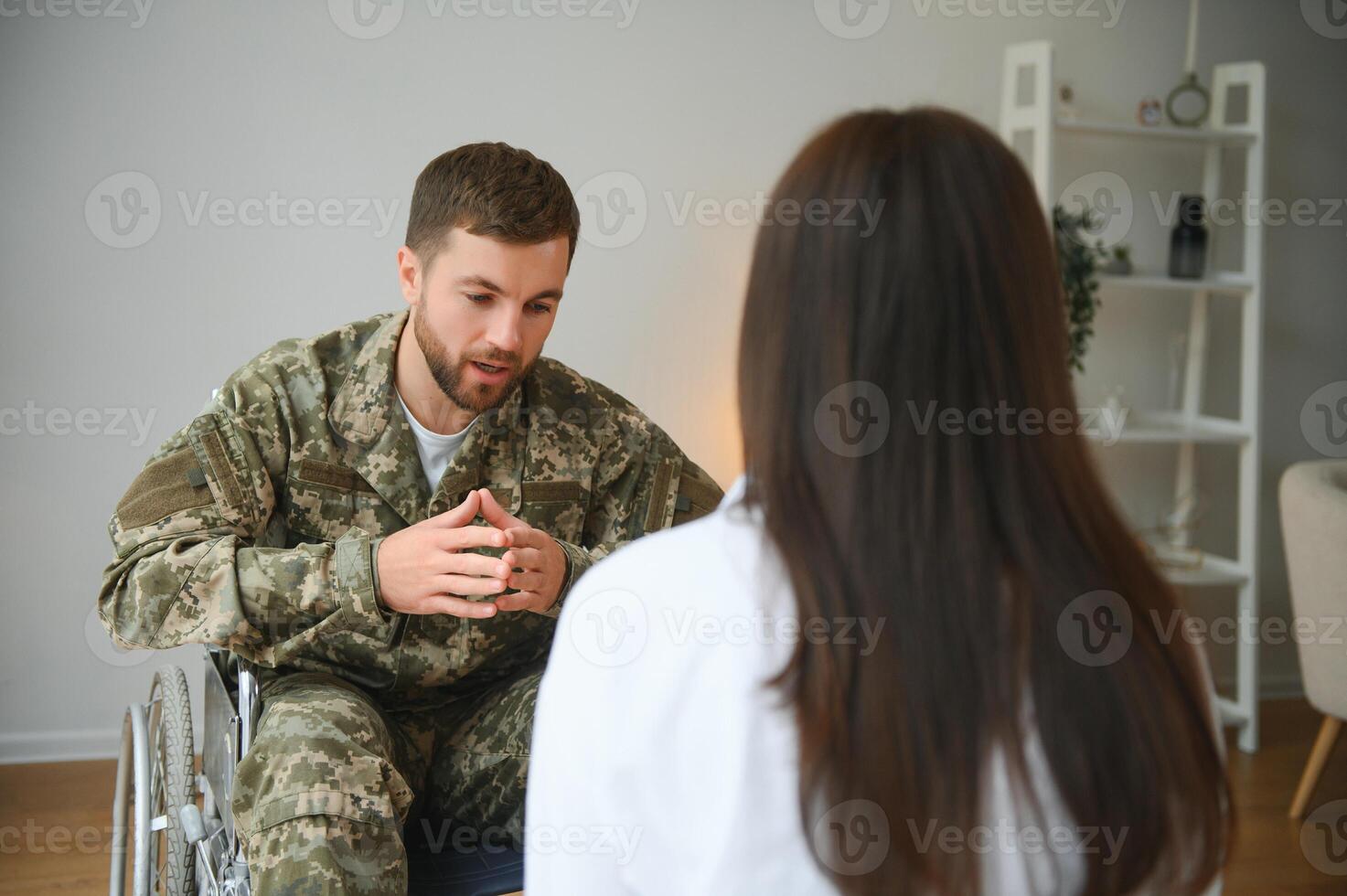depressivo cara dentro camuflar uniforme paralisado soldado dentro cadeira de rodas visitando fêmea psicólogo. foto