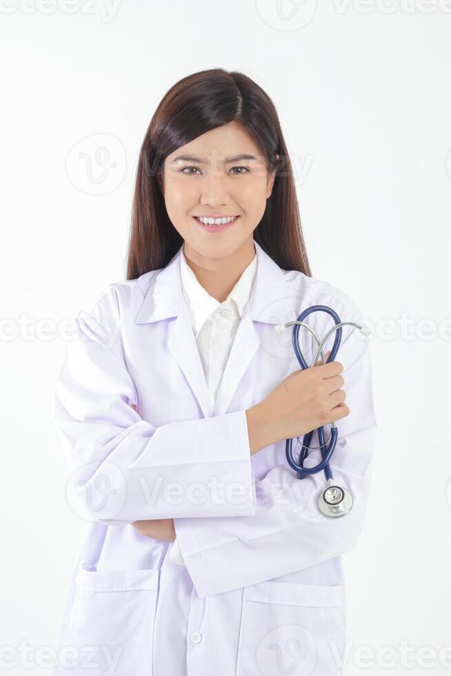 retrato. lindo ásia fêmea doutor. em pé com braços cruzado segurando uma estetoscópio. conceito do médico Serviços dentro hospitais. branco fundo foto