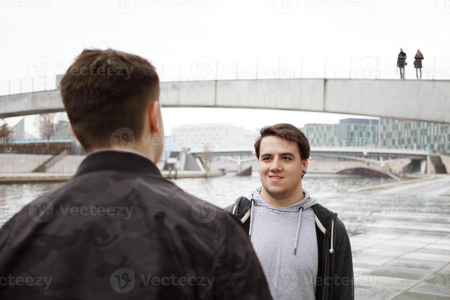 dois masculino Adolescência amigos tendo uma conversação de a rio foto