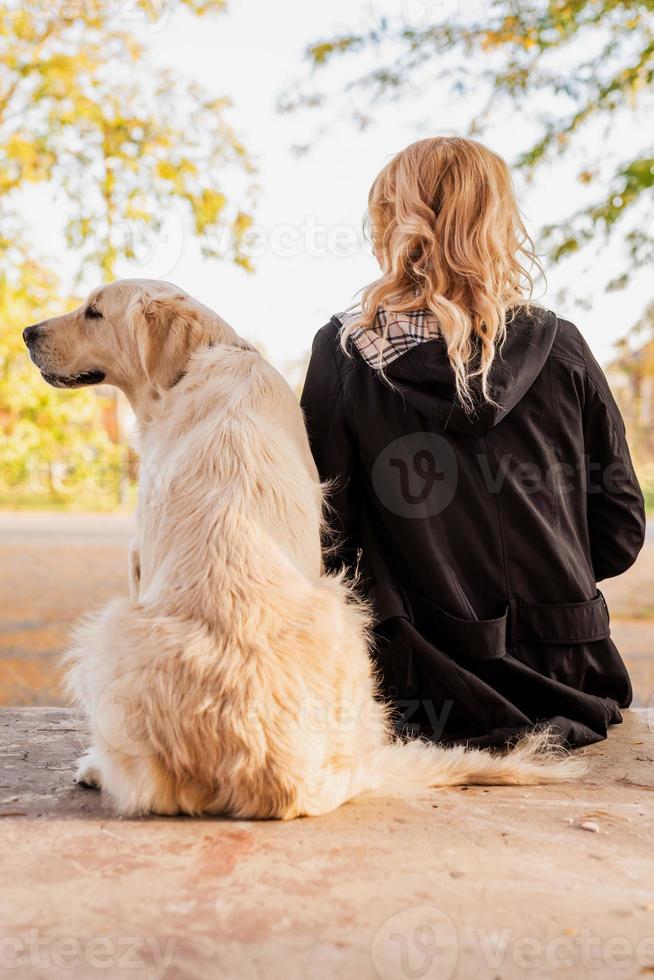 mulher e seu cachorro retriever sentados na rua juntos foto