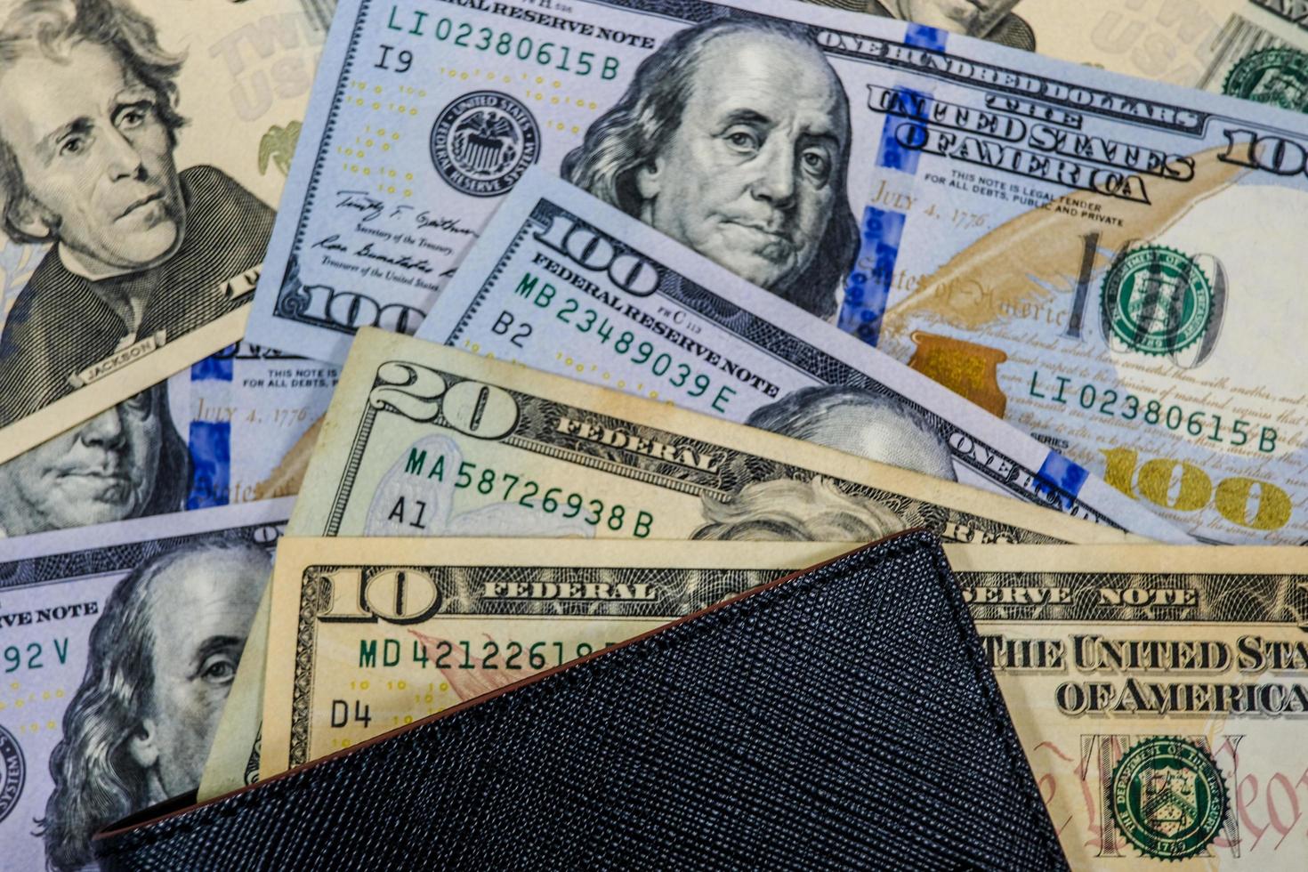 pilha de muitas notas de dólar americano com carteira preta como fundo de dinheiro para economia de investimento e conceito de compras. foto