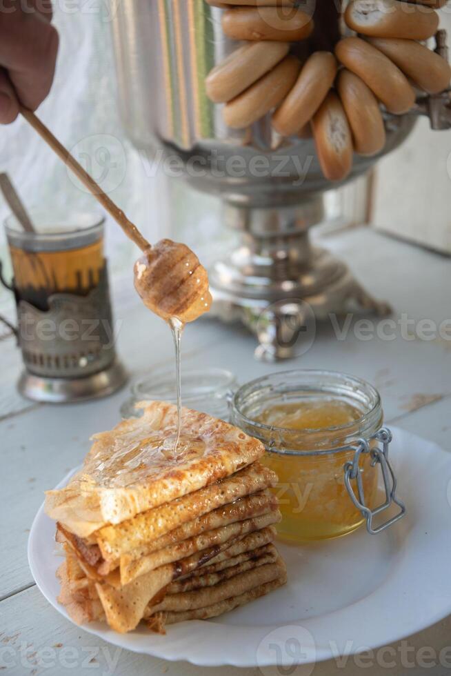 russo panquecas com querida e uma copo do chá a partir de uma vintage samovar maslenitsa festival conceito foto