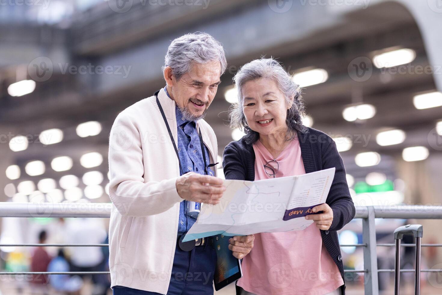 ásia ativo Senior aposentadoria casal é olhando às a mapa para direção dentro aeroporto terminal para segundo lua de mel pensionista viagem e urbano metro trem transporte conceito foto