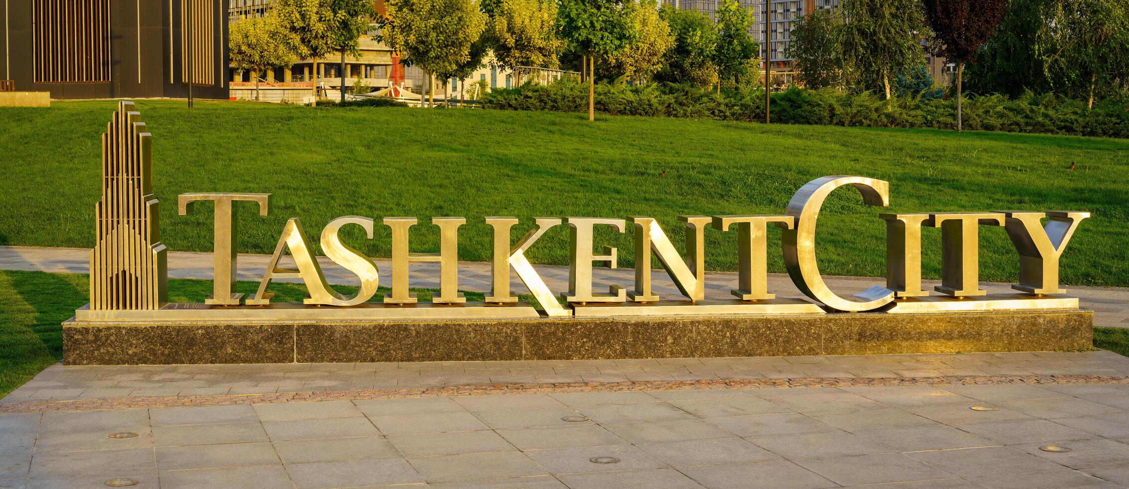 uzbequistão, Tashkent - Junho 17, 2023 a logotipo do a Tashkent cidade parque aceso de Sol em uma calçada e verde Relva fundo. foto