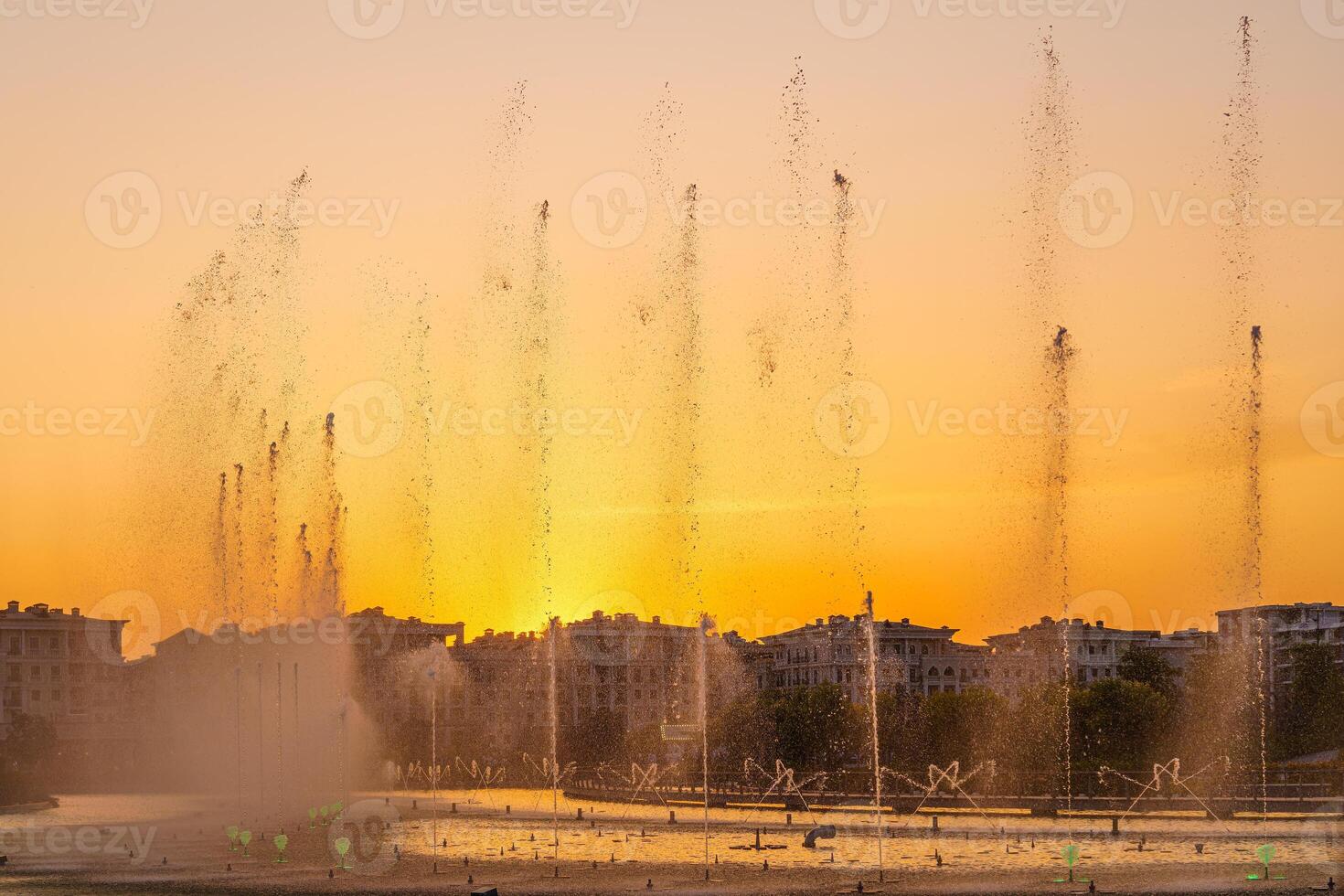 grande fontes em a artificial lago, iluminado de luz solar às pôr do sol dentro Tashkent cidade parque às horário de verão. foto