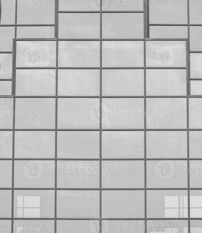 Preto e branco fragmento do uma moderno escritório prédio. abstrato geométrico fundo. parte do a fachada do uma arranha-céu com vidro janelas. foto