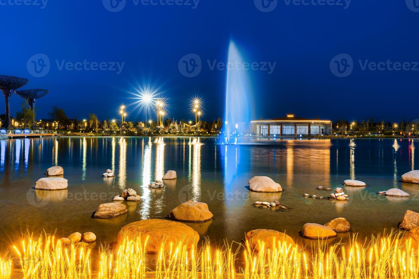 borrado fonte água fluxos dentro a artificial lago dentro uma noite parque com lanternas e decorações. foto