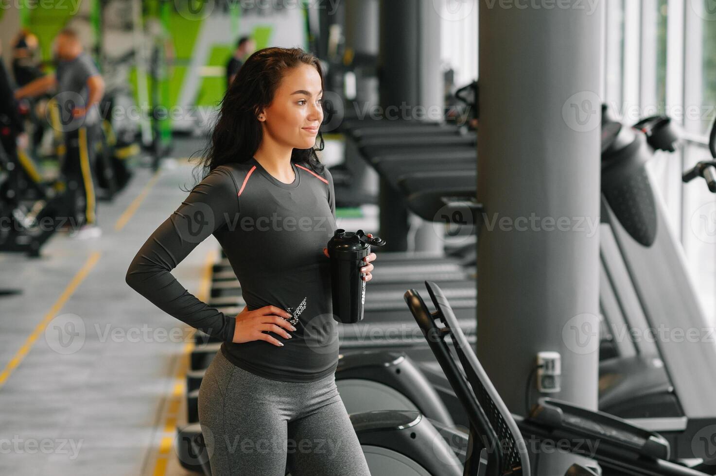 jovem lindo mulher bebendo água dentro Esportes academia. foto