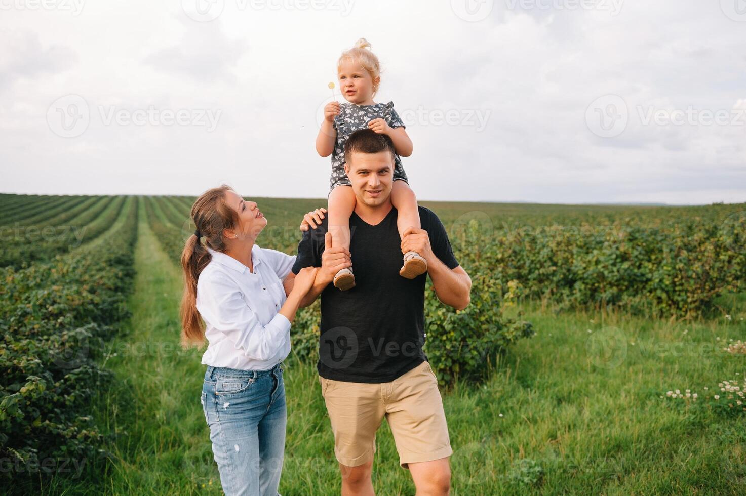 feliz família com pequeno filha gastos Tempo juntos dentro ensolarado campo. foto