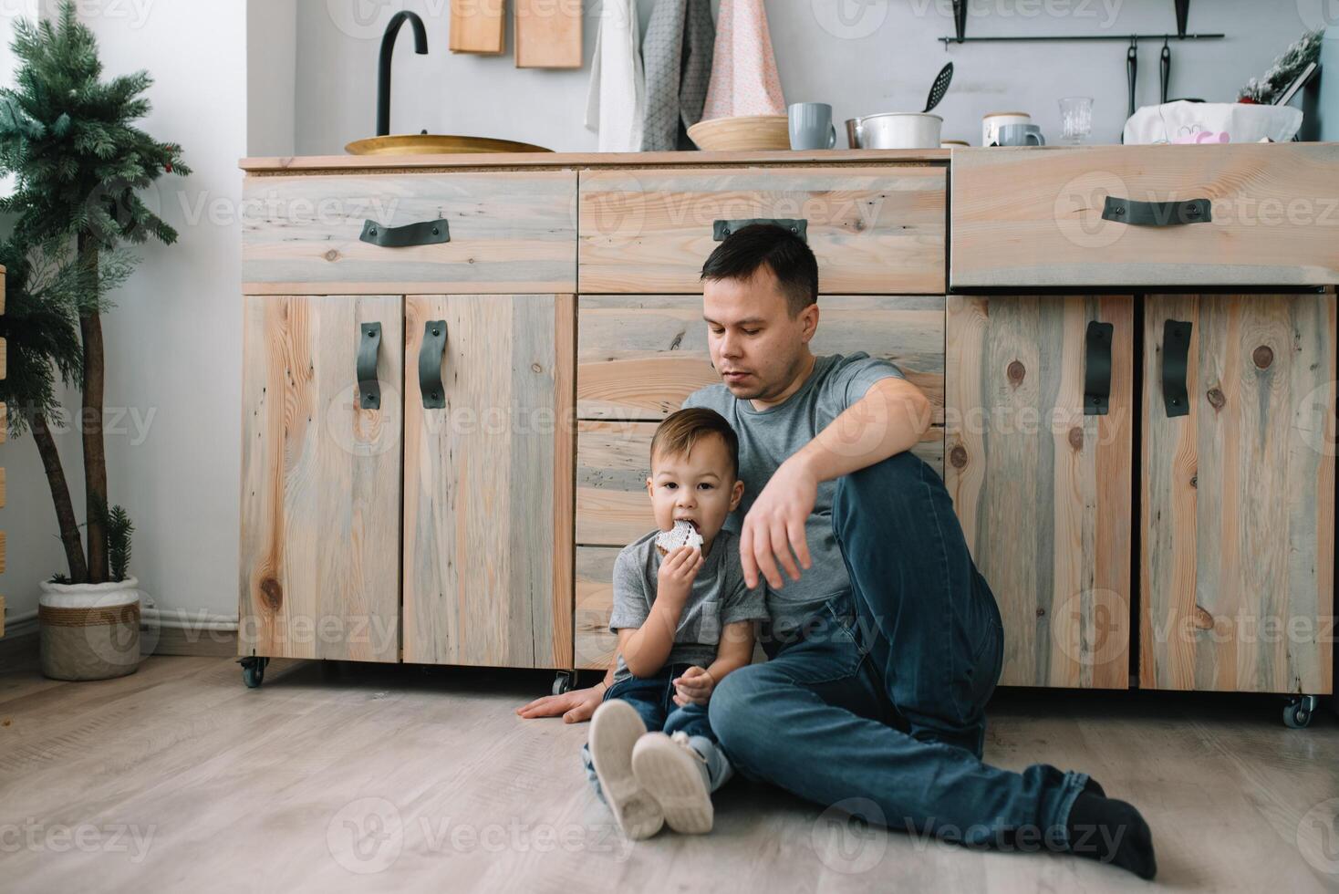 jovem homem e dele filho com forno Folha dentro cozinha. pai com pequeno filho em a cozinha foto