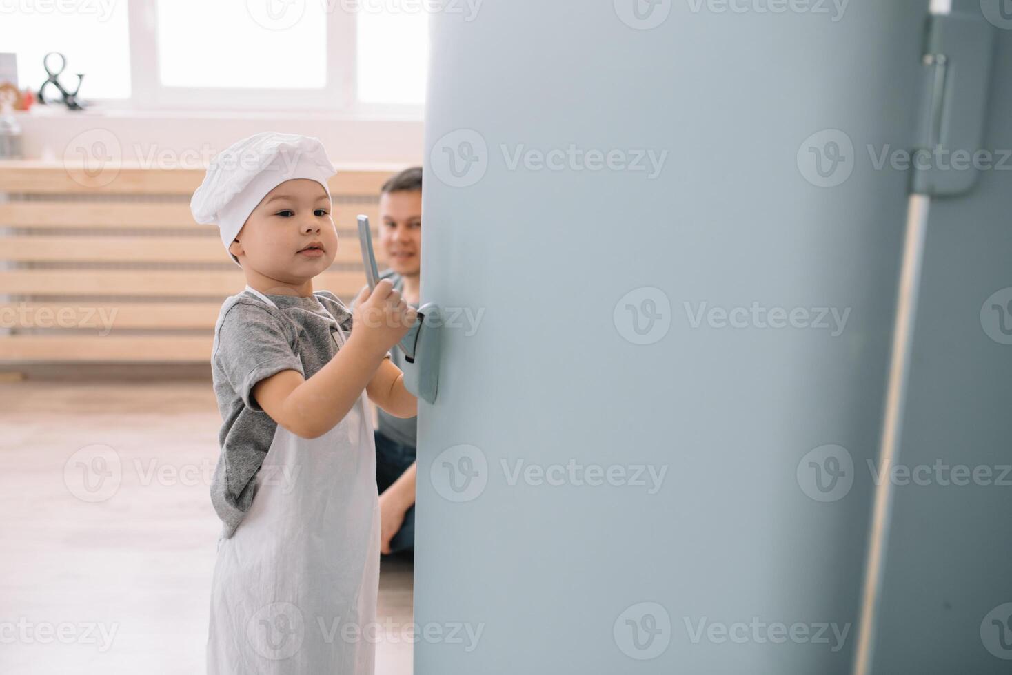 jovem homem e dele filho com forno Folha dentro cozinha. pai com pequeno filho em a cozinha. foto