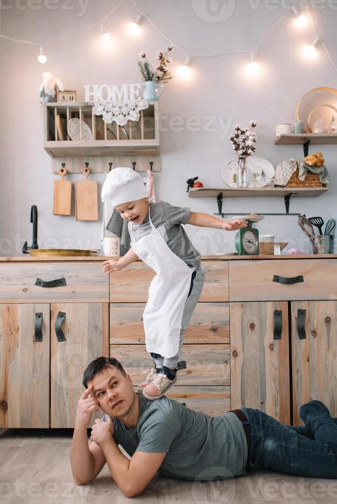 jovem homem e dele filho com forno Folha dentro cozinha. pai com pequeno filho em a cozinha foto