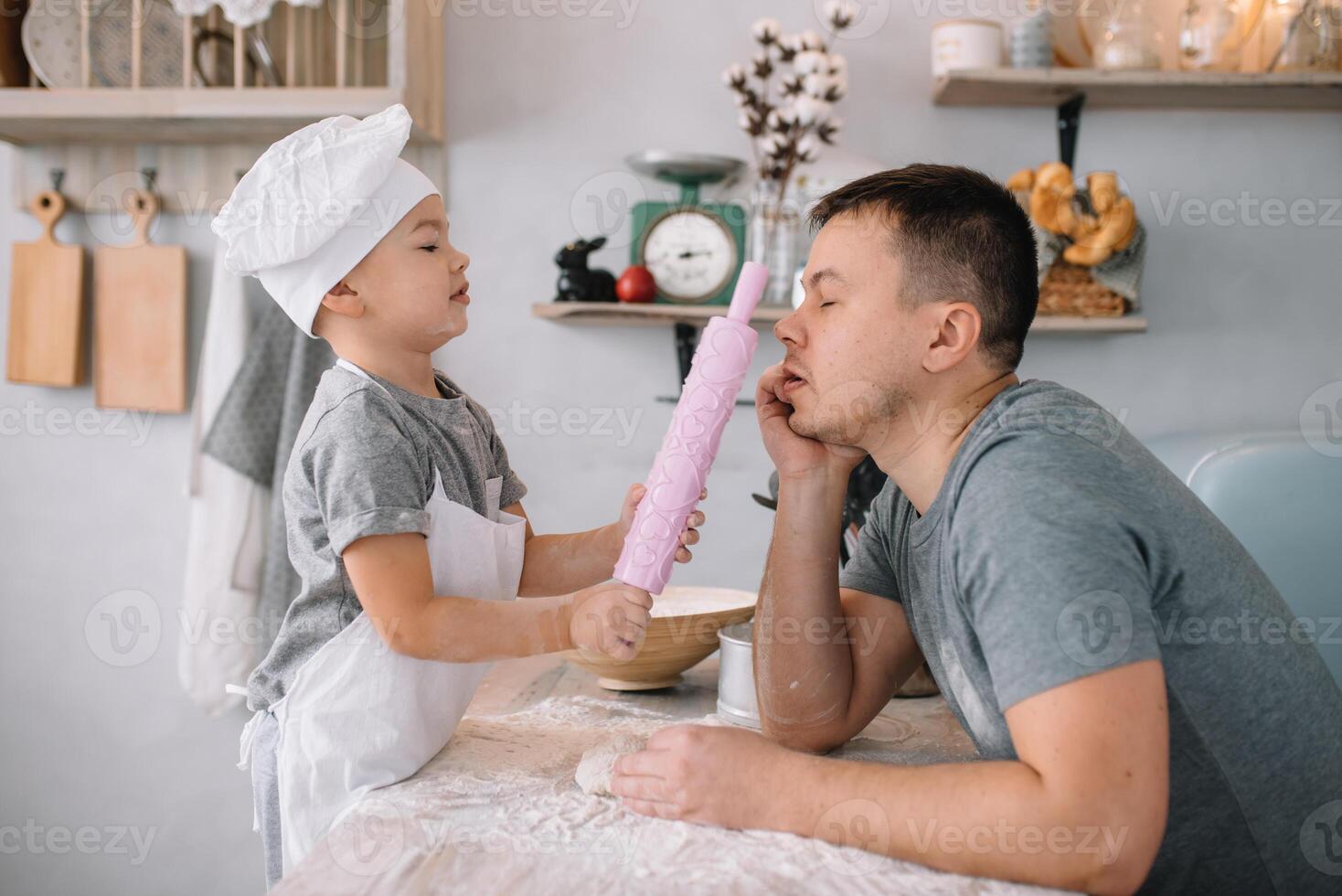 jovem homem e dele filho com forno Folha dentro cozinha. pai com pequeno filho em a cozinha. foto