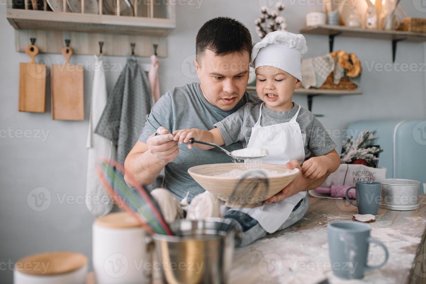 jovem homem e dele filho com forno Folha dentro cozinha. pai com pequeno filho em a cozinha. foto