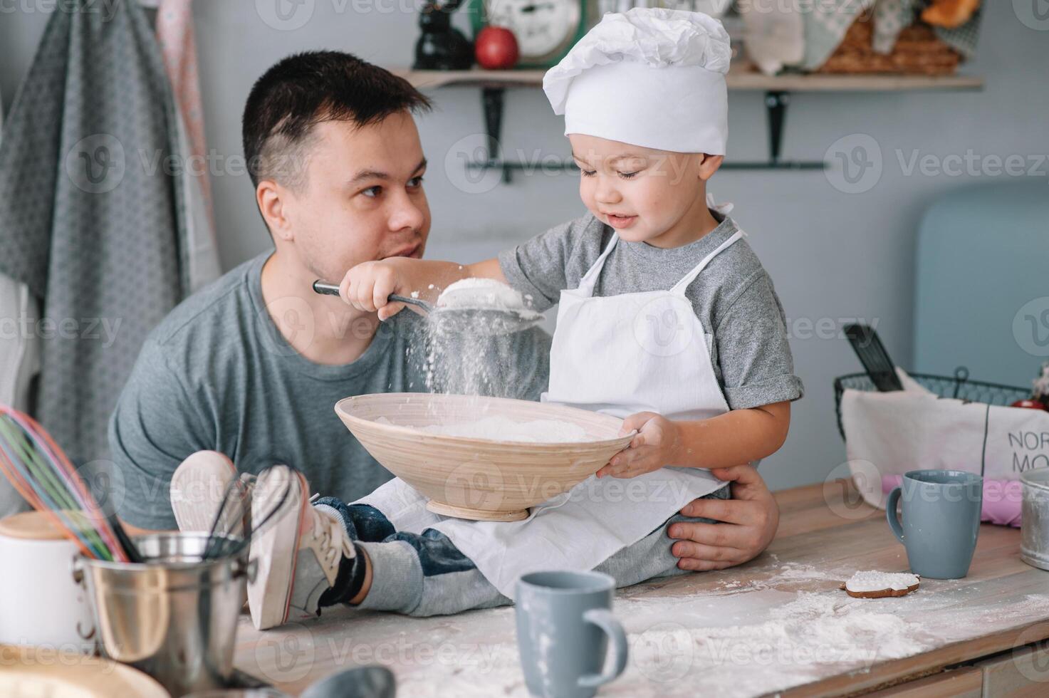 jovem homem e dele filho com forno Folha dentro cozinha. pai com pequeno filho em a cozinha foto