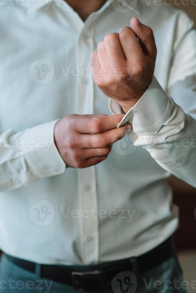 do noivo manhã. Casamento preparando. homem dentro branco camisa colocando em abotoaduras. o negócio vestir código foto