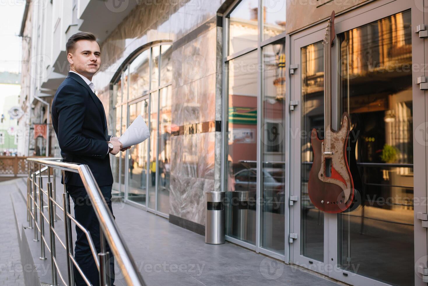 jovem o negócio homem com documentos e Móvel telefone perto do moderno prédio. foto