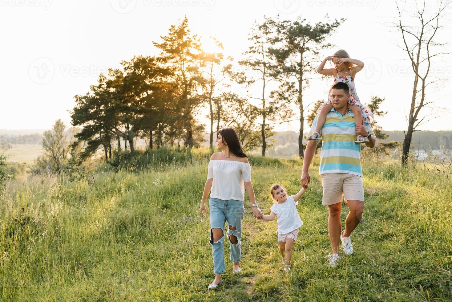 cor foto do sorridente jovem pais e dois crianças, descansar e ter Diversão dentro natureza. amor, família e feliz infância estilo de vida conceito.