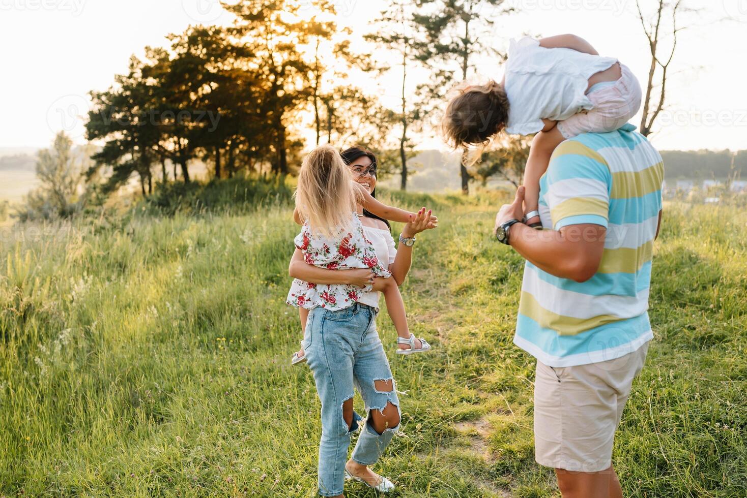 cor foto do sorridente jovem pais e dois crianças, descansar e ter Diversão dentro natureza. amor, família e feliz infância estilo de vida conceito.